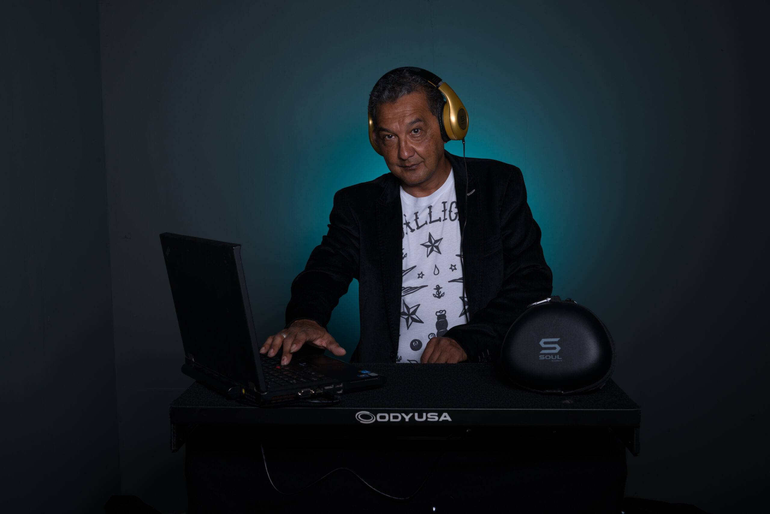 Roy (DJ Funkey R) achter zijn DJ-set met koptelefoon, klaar om muziek te draaien tijdens een feest of evenement.